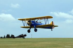Biplan bleu et jaune en vol à l’Aérodrome de Saint-Hubert